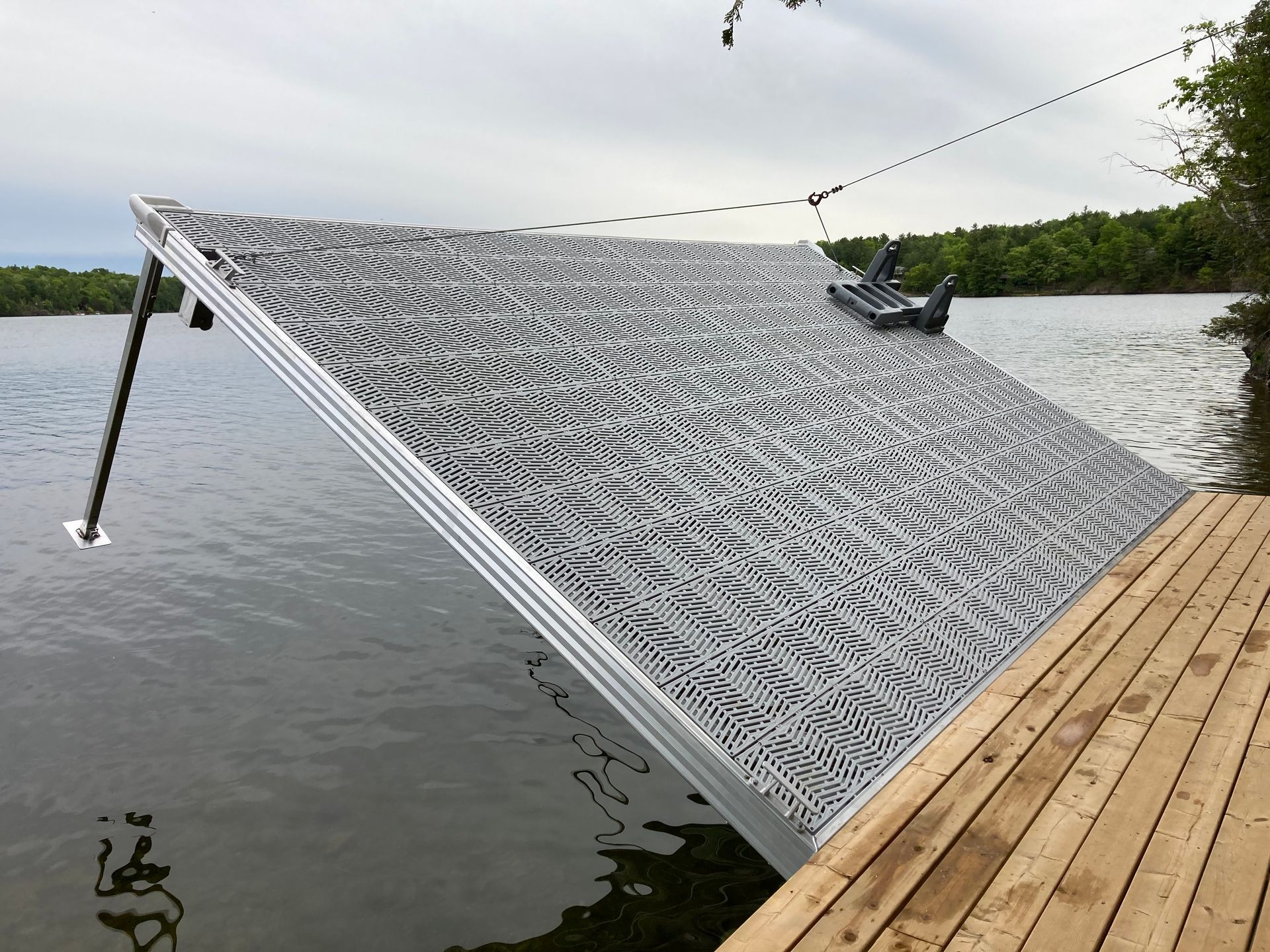 Metal dock ramp positioned at steep angle above lake water, connected to wooden shoreline deck.