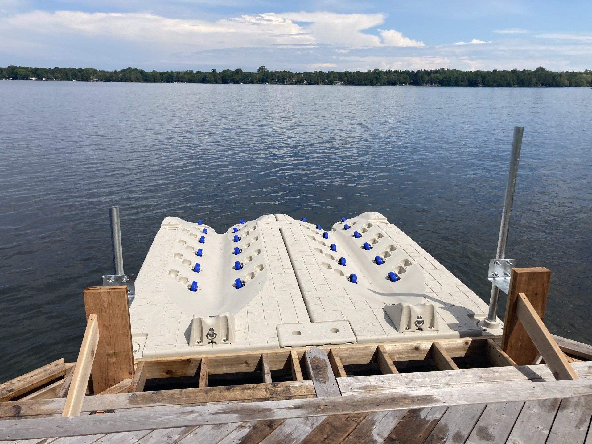 A dock with blue buoys on it is in the middle of a lake