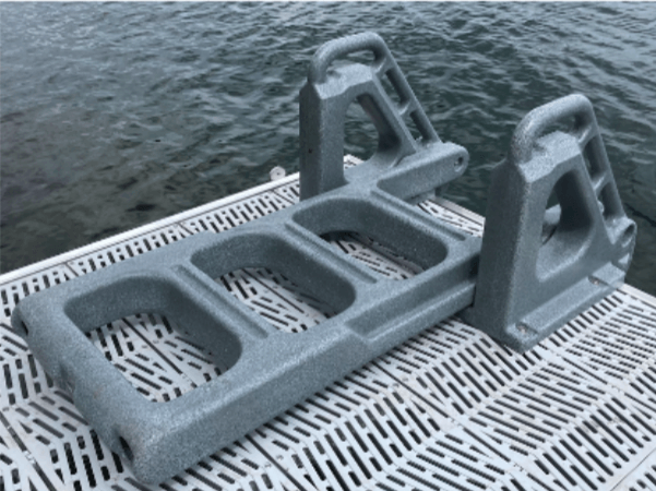 A gray ladder is sitting on a dock next to a body of water