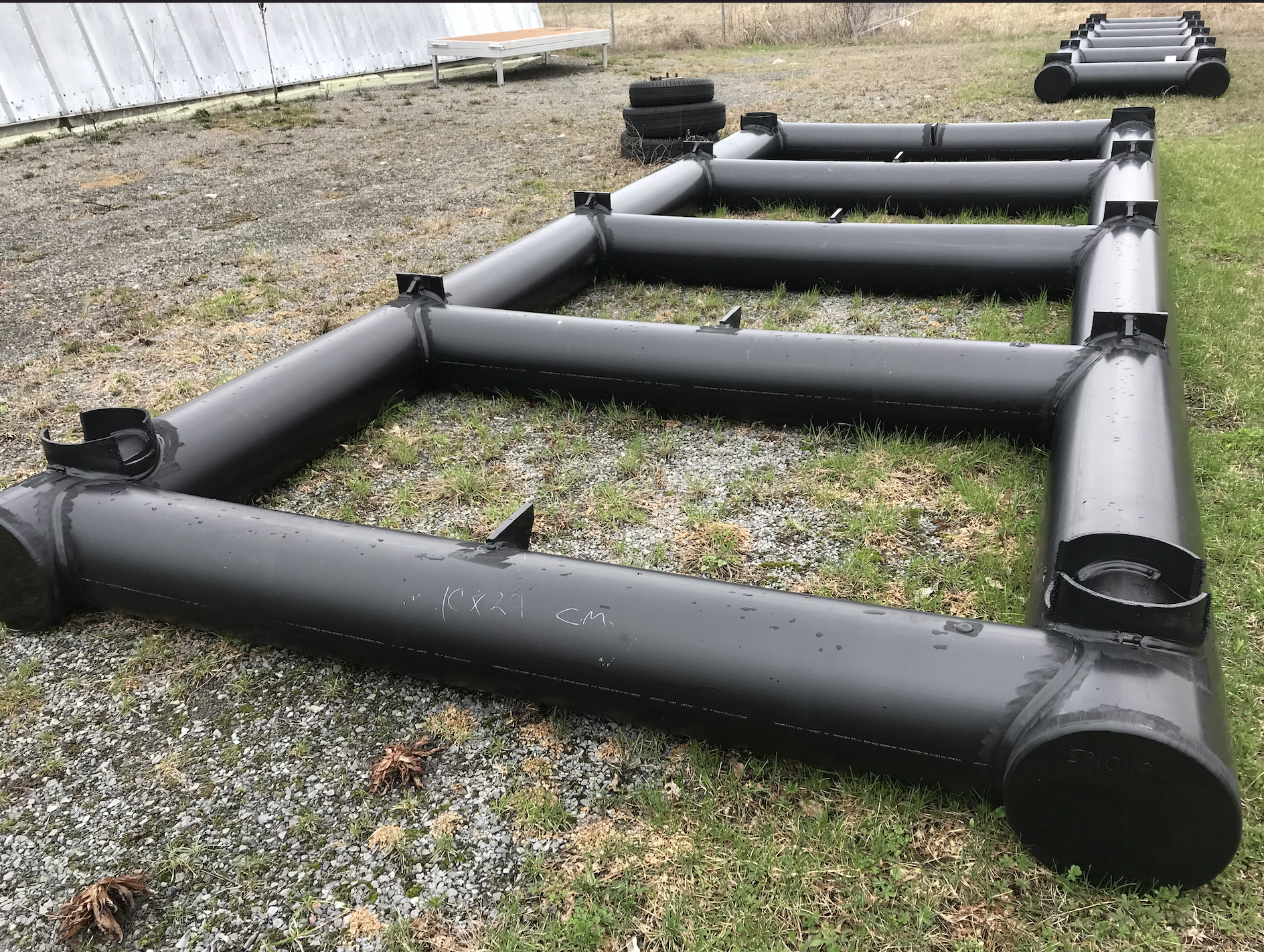 A row of black pipes are sitting in the grass