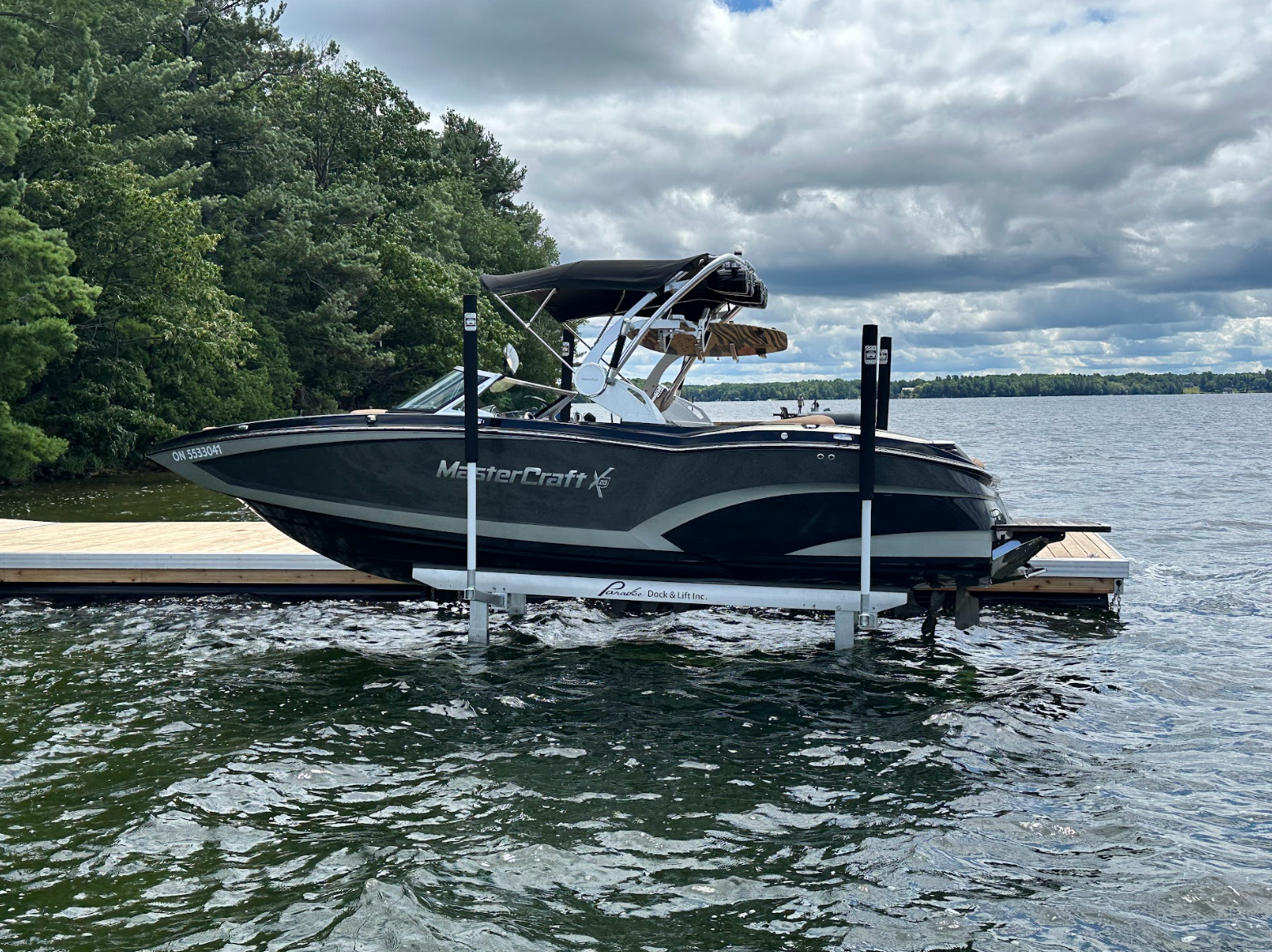 A boat is docked on a boat lift on a lake.