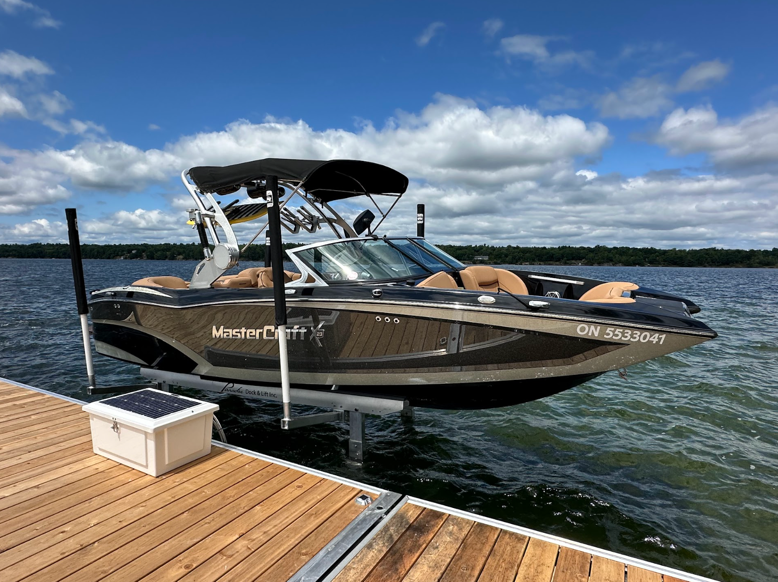 A boat is on a boat lift at a dock on a lake.
