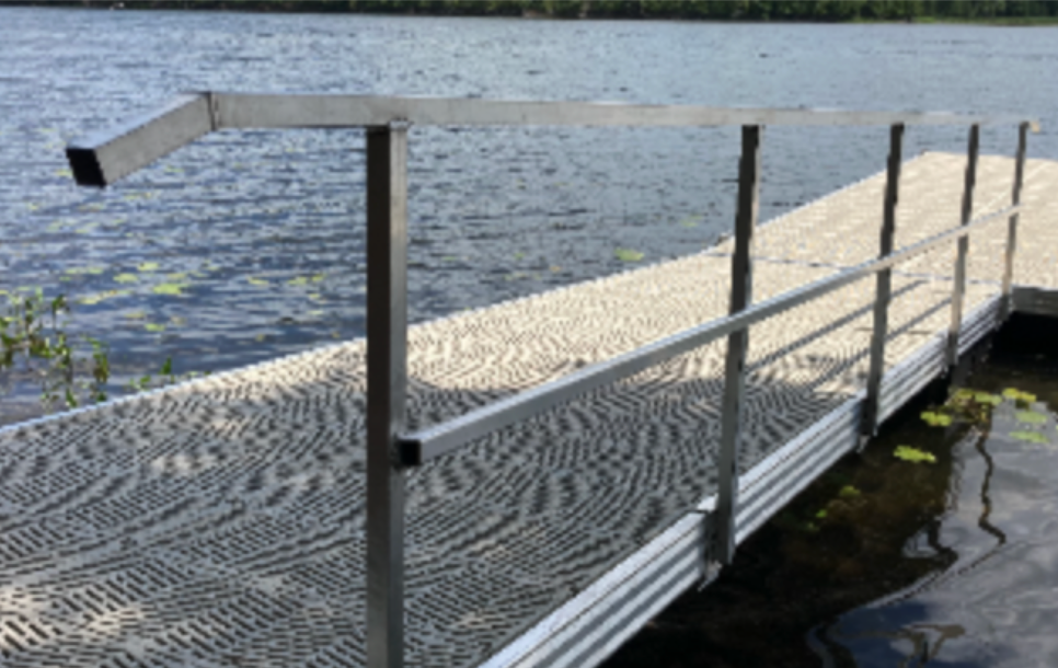 A dock with a metal railing leading to a body of water.