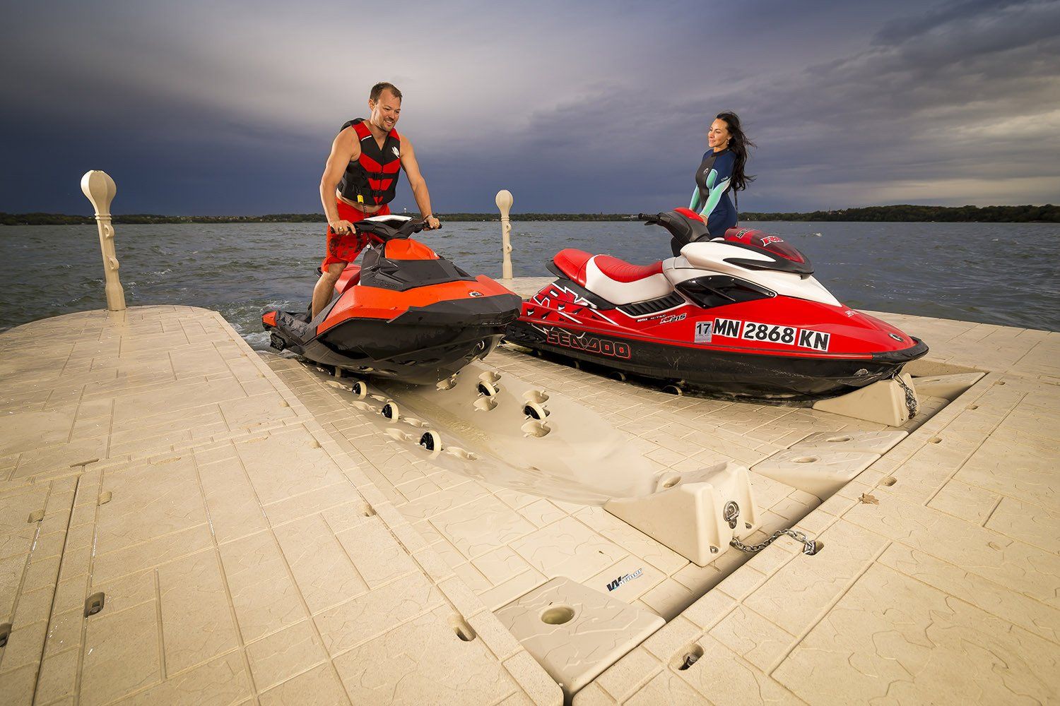 A man and a woman are riding jet skis on a dock.