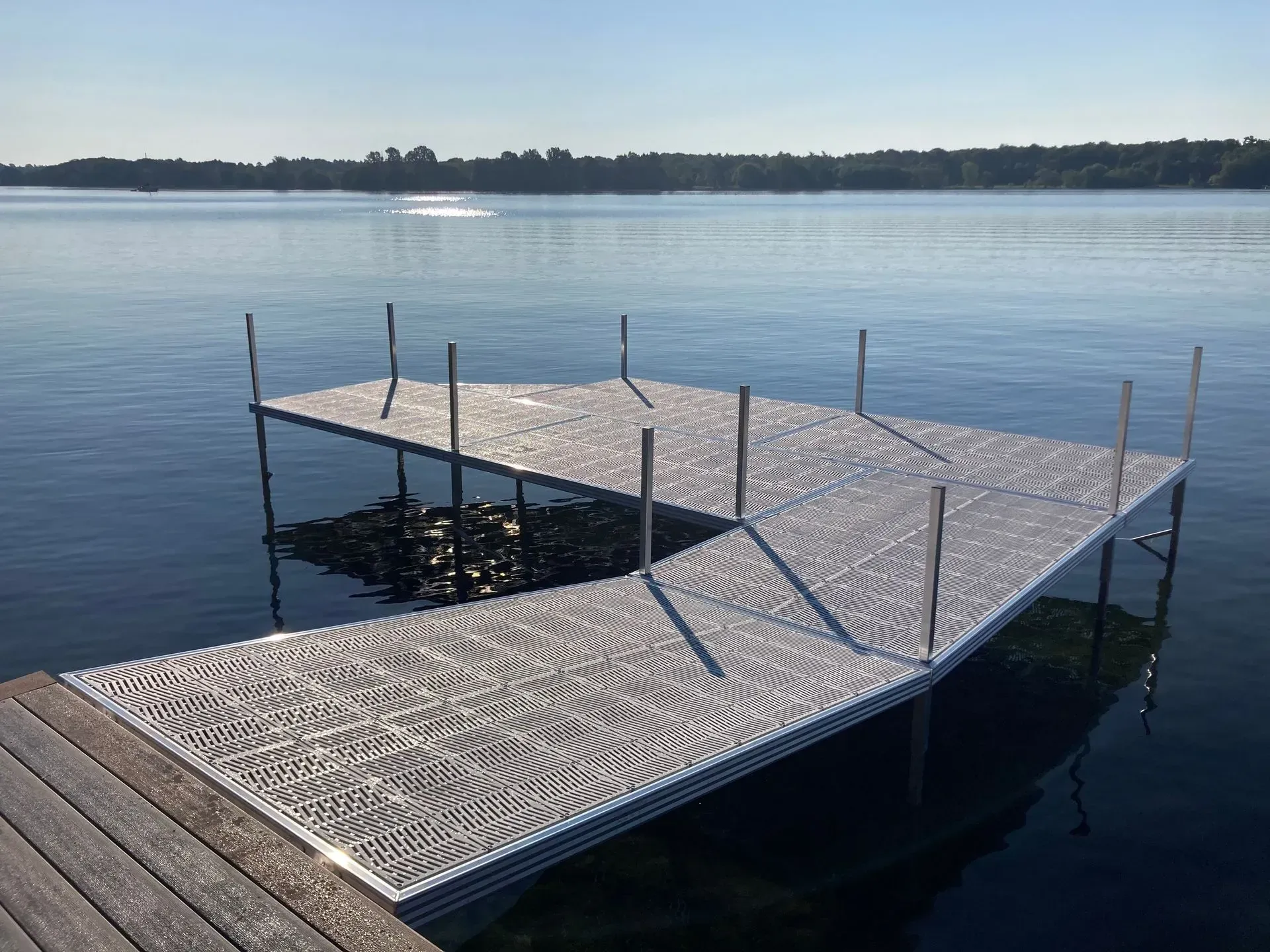Aluminum dock with maintenance-free decking extending over a calm lake on a clear summer day.