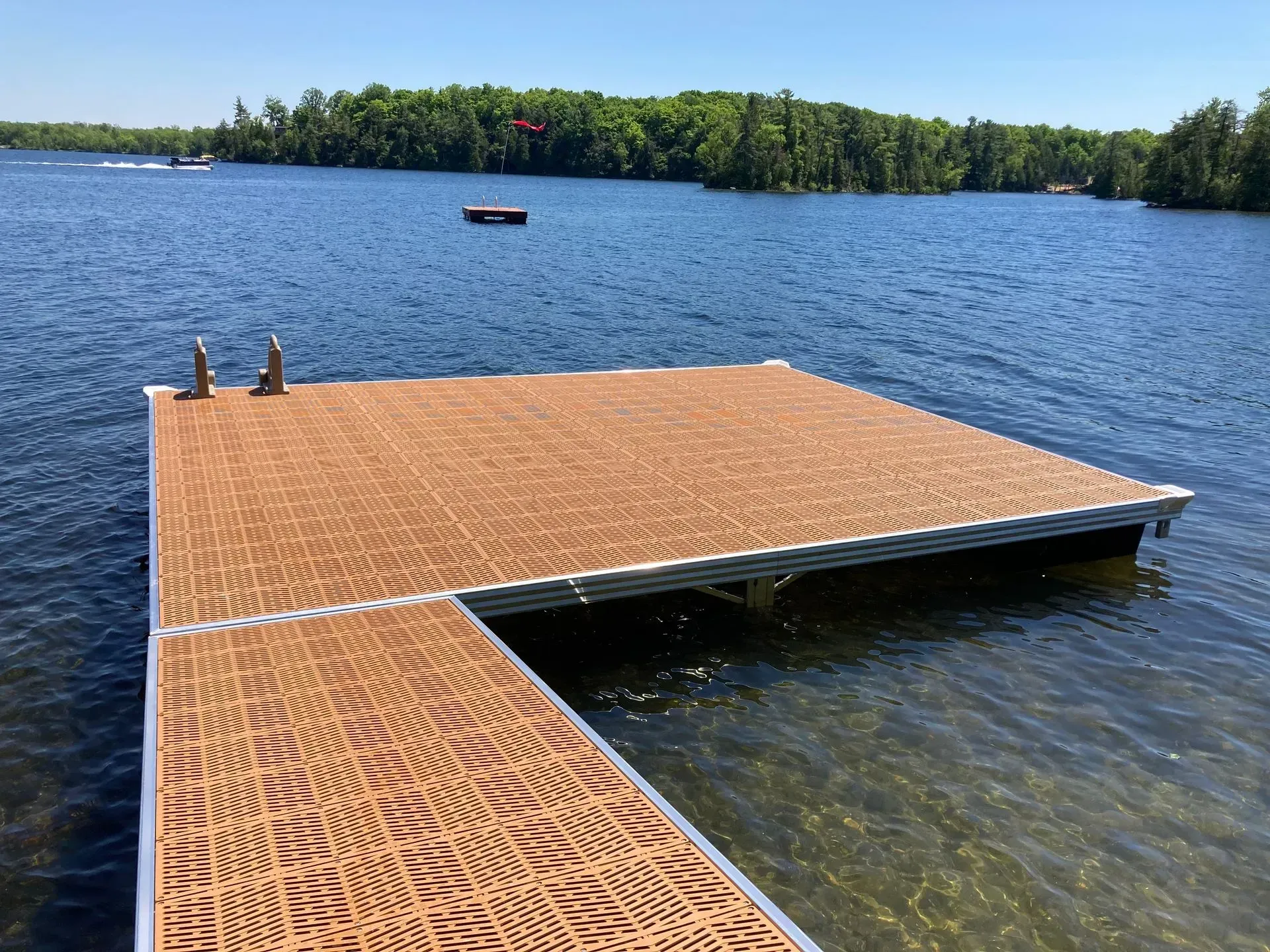 Wide modular dock with brown decking and aluminum framing extending into a calm Ontario lake.