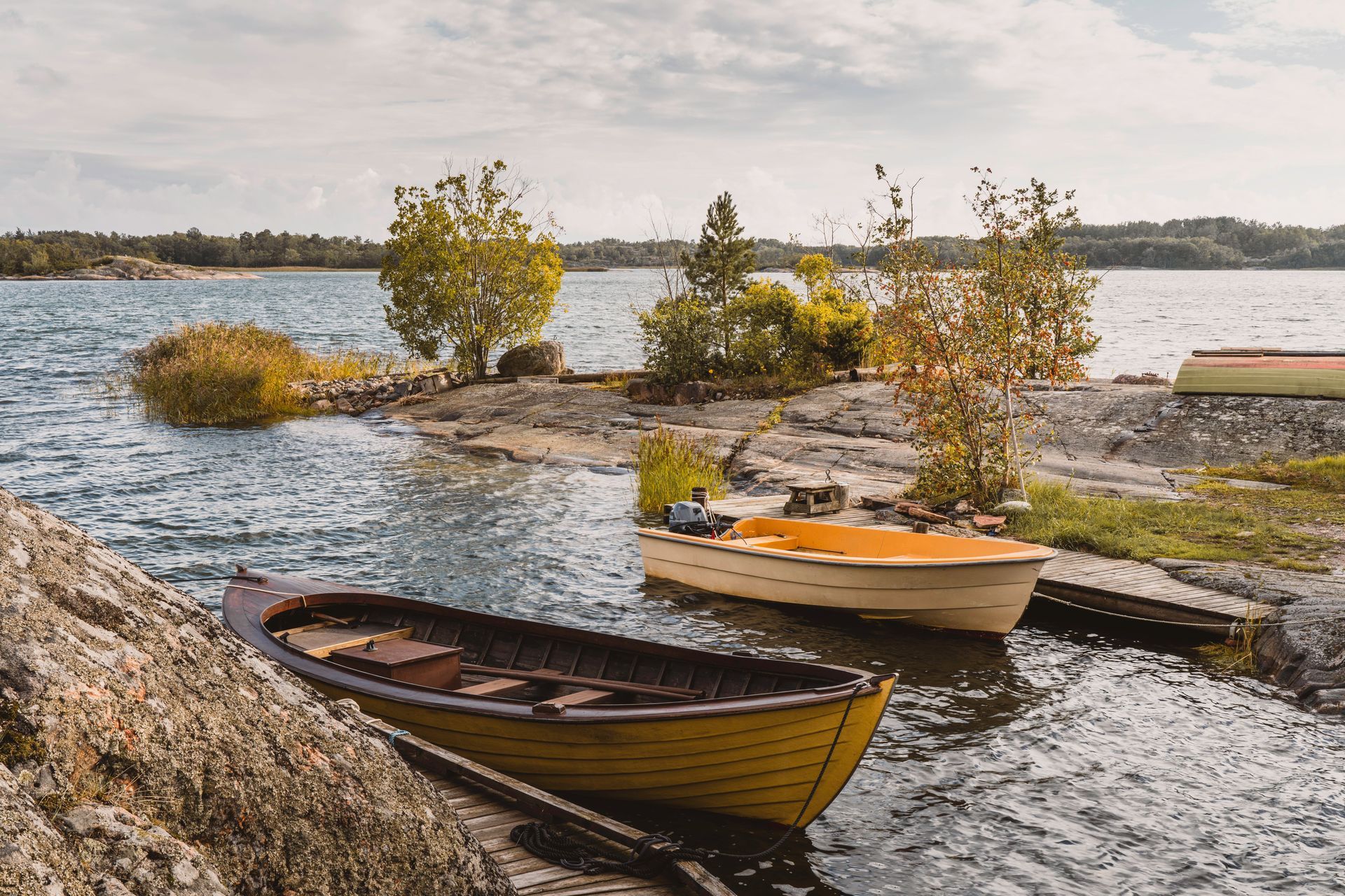 Rocky lake shoreline with pine trees and small boats pulled up on the rock