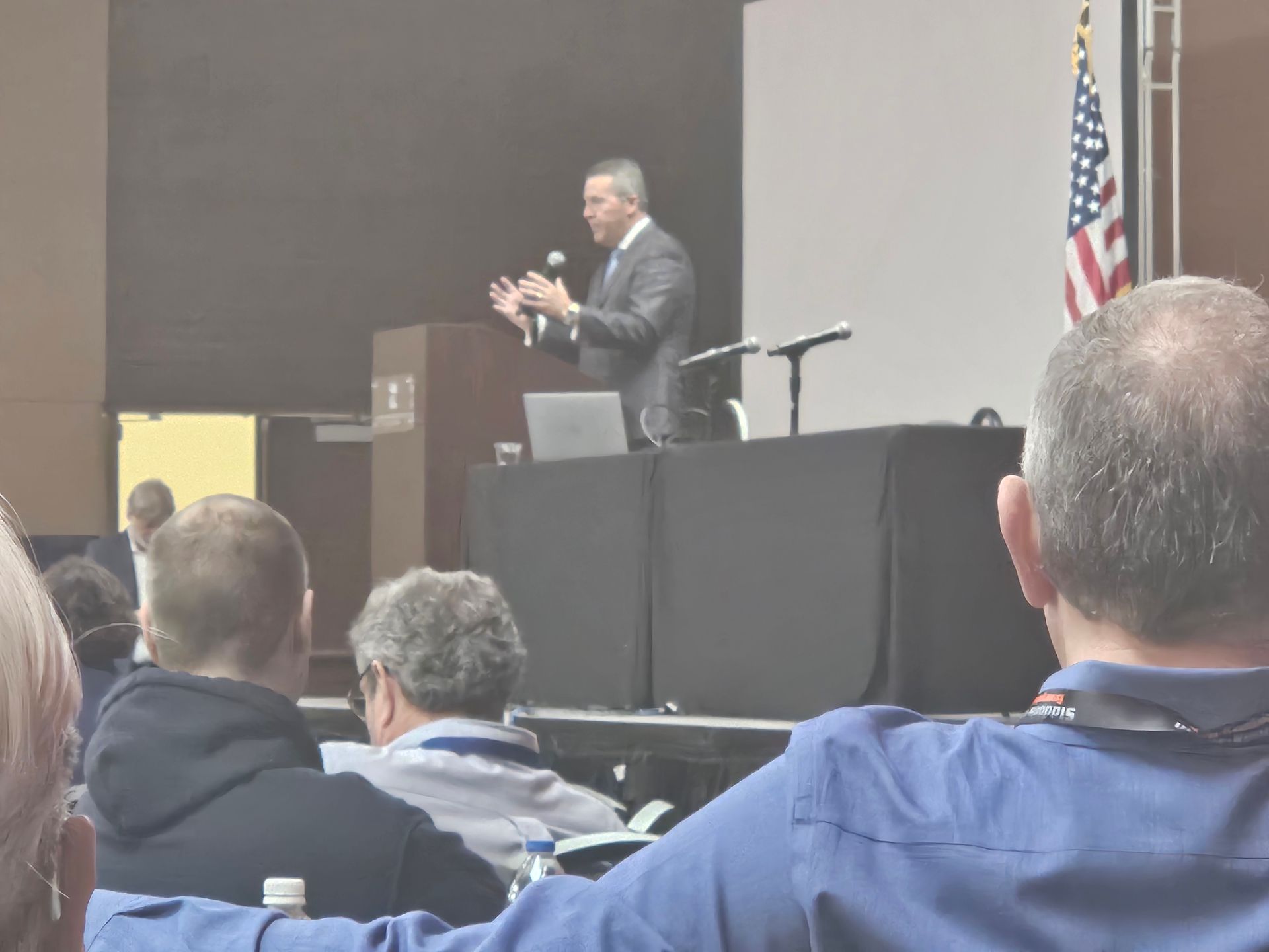 A man stands at a podium giving a presentation to a group of people
