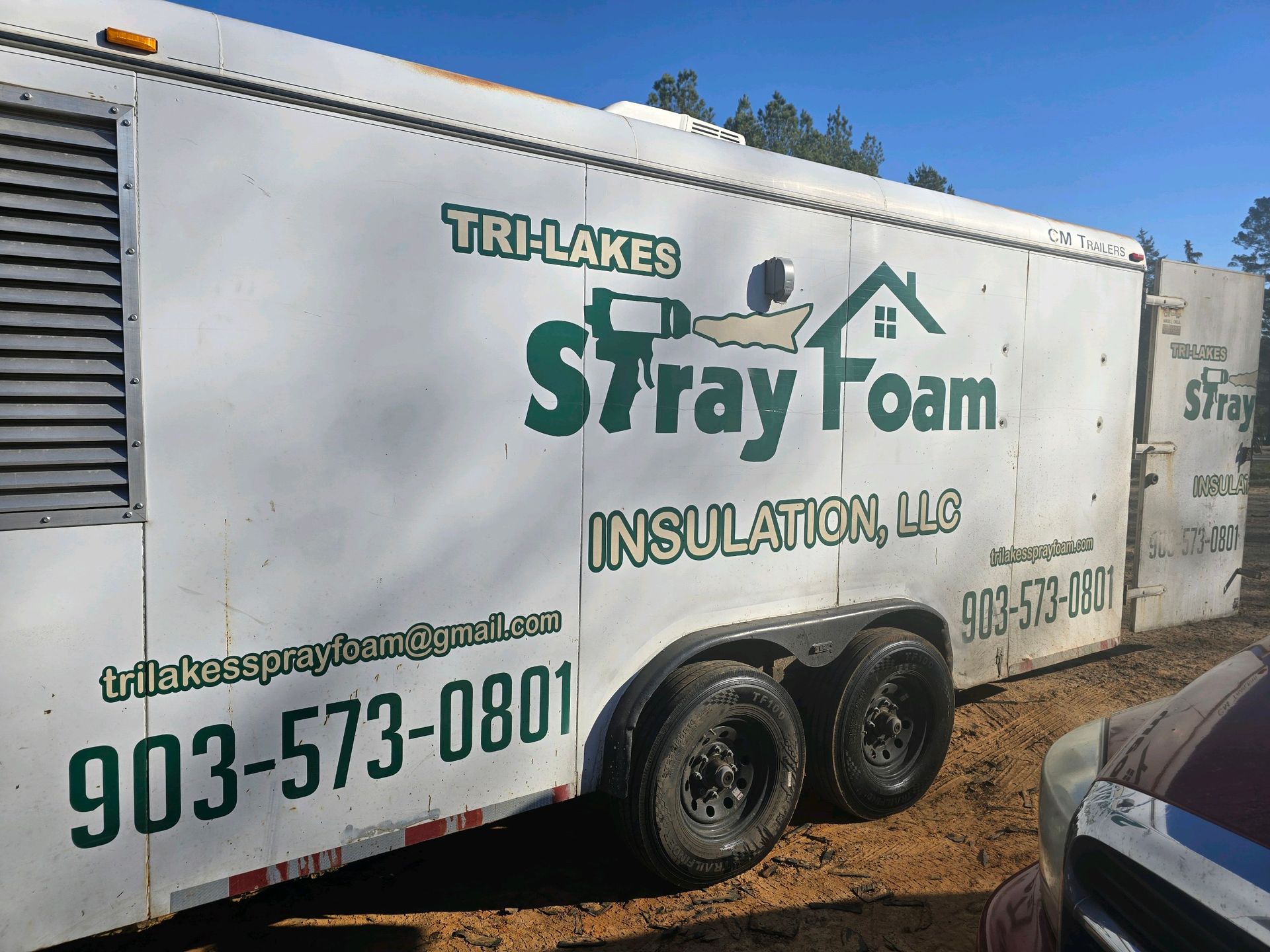 A trailer for SprayFoam Insulation llc is parked in the dirt