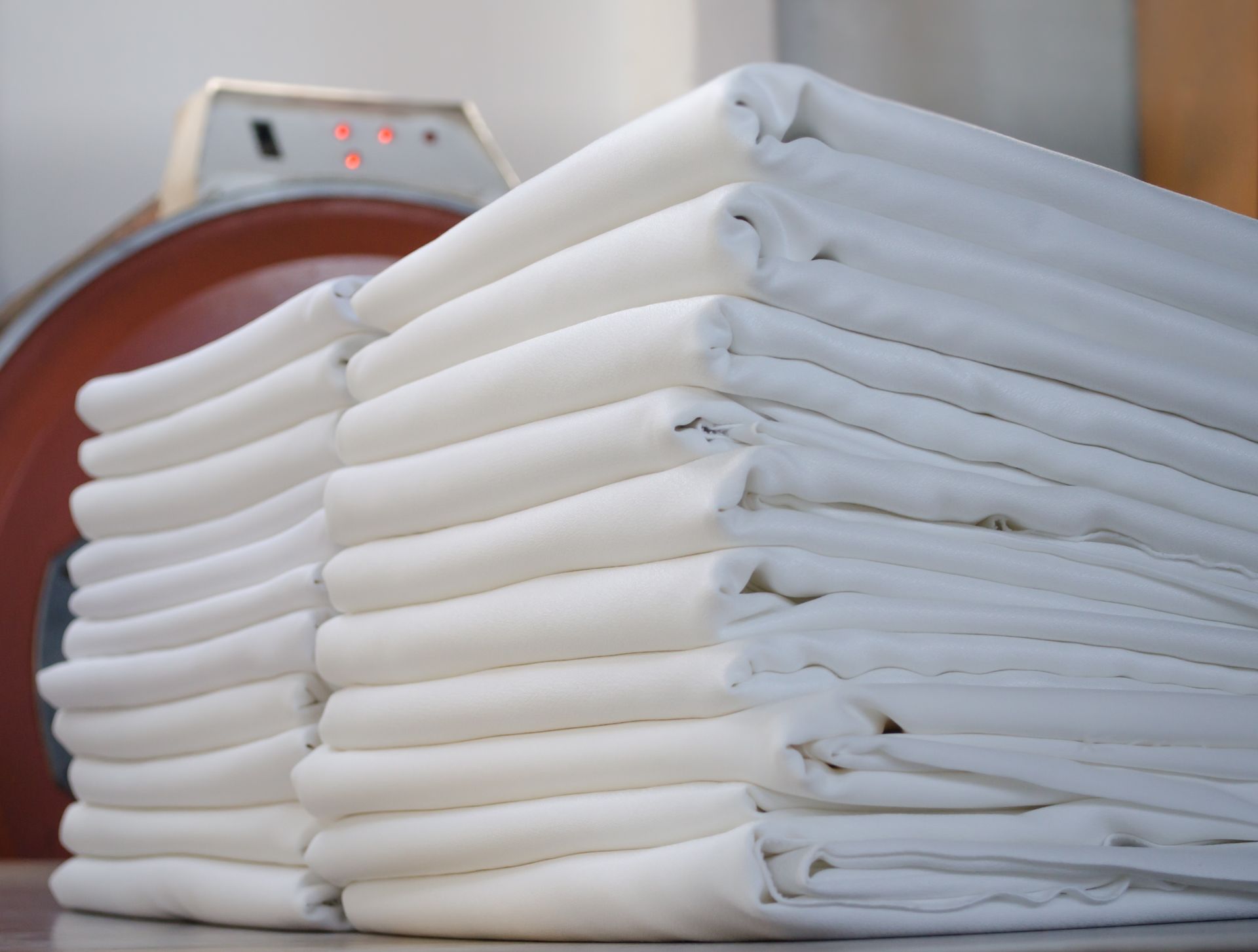 A stack of white fabrics in a laundry room.