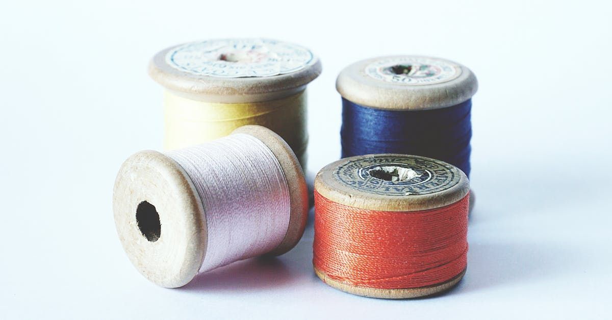 Four spools of thread are sitting next to each other on a white surface.
