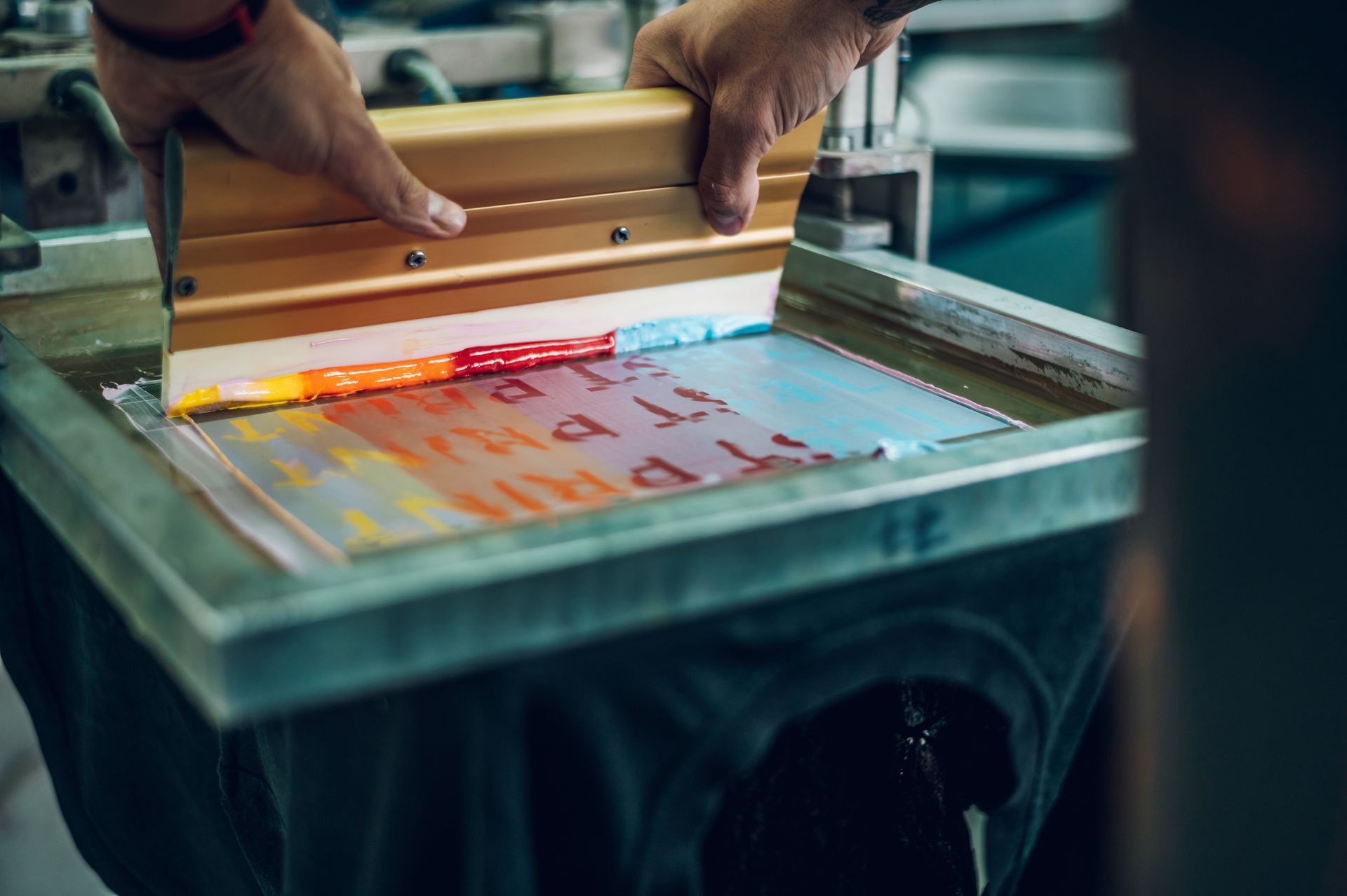 A person is using a screen printing machine to print a piece of paper.