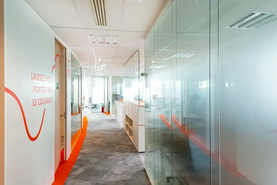 Un long couloir dans un immeuble de bureaux avec des murs en verre. Aménagement de bureaux et locaux professionnels - SPAC