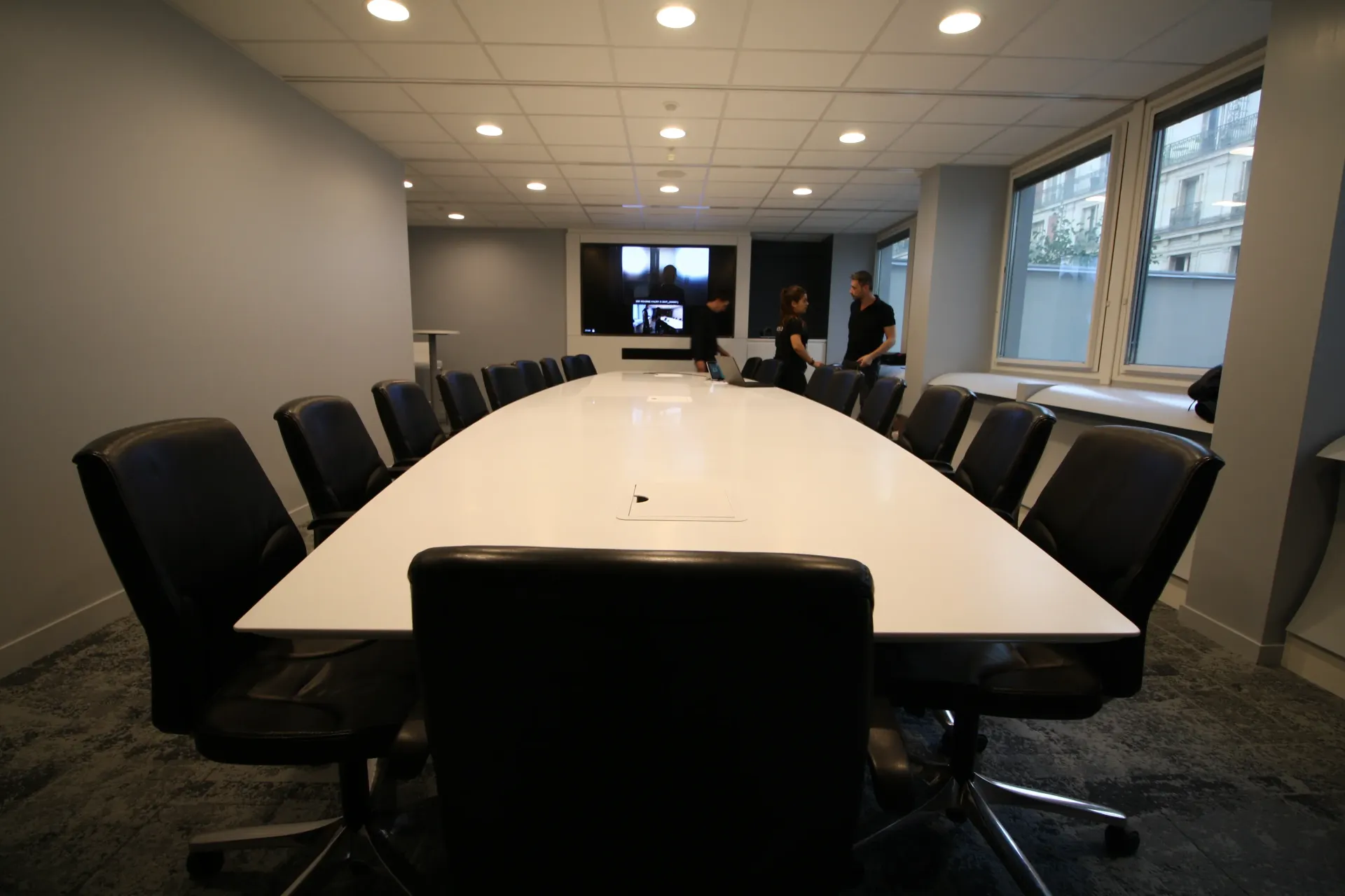 Une salle de conférence avec une longue table blanche et des chaises. SPAC