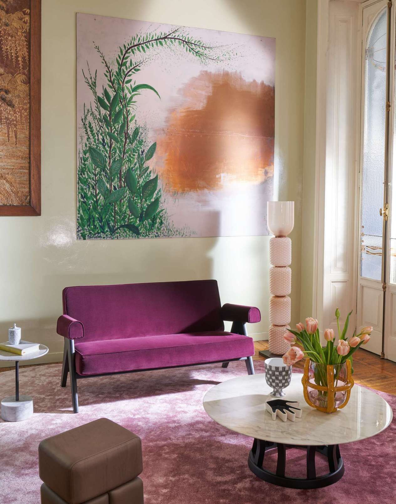 Een woonkamer met een paarse bank en een schilderij aan de muur