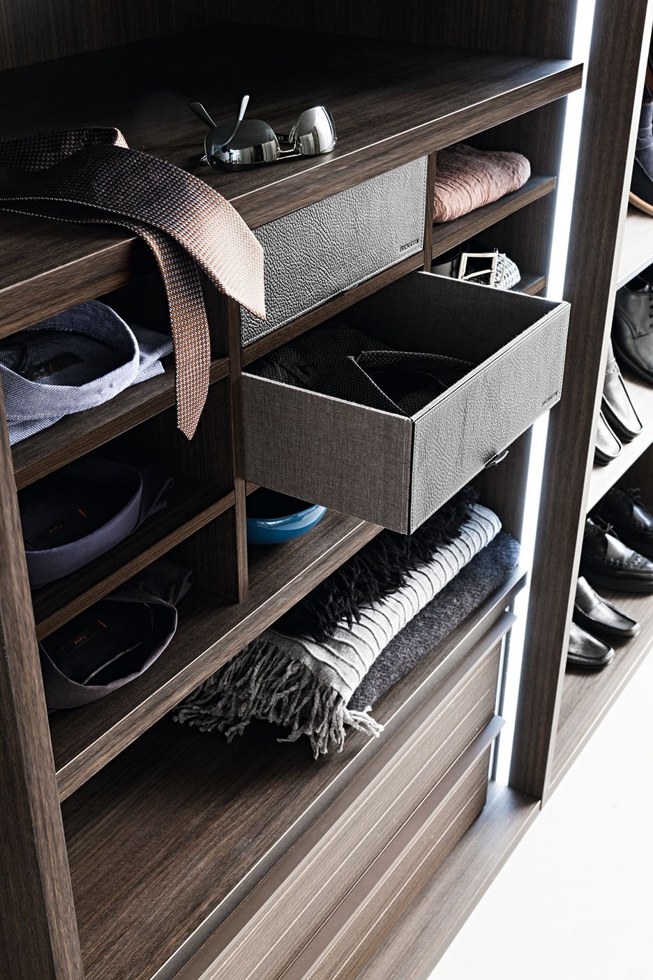 Een kast met een open lade gevuld met kleding en schoenen