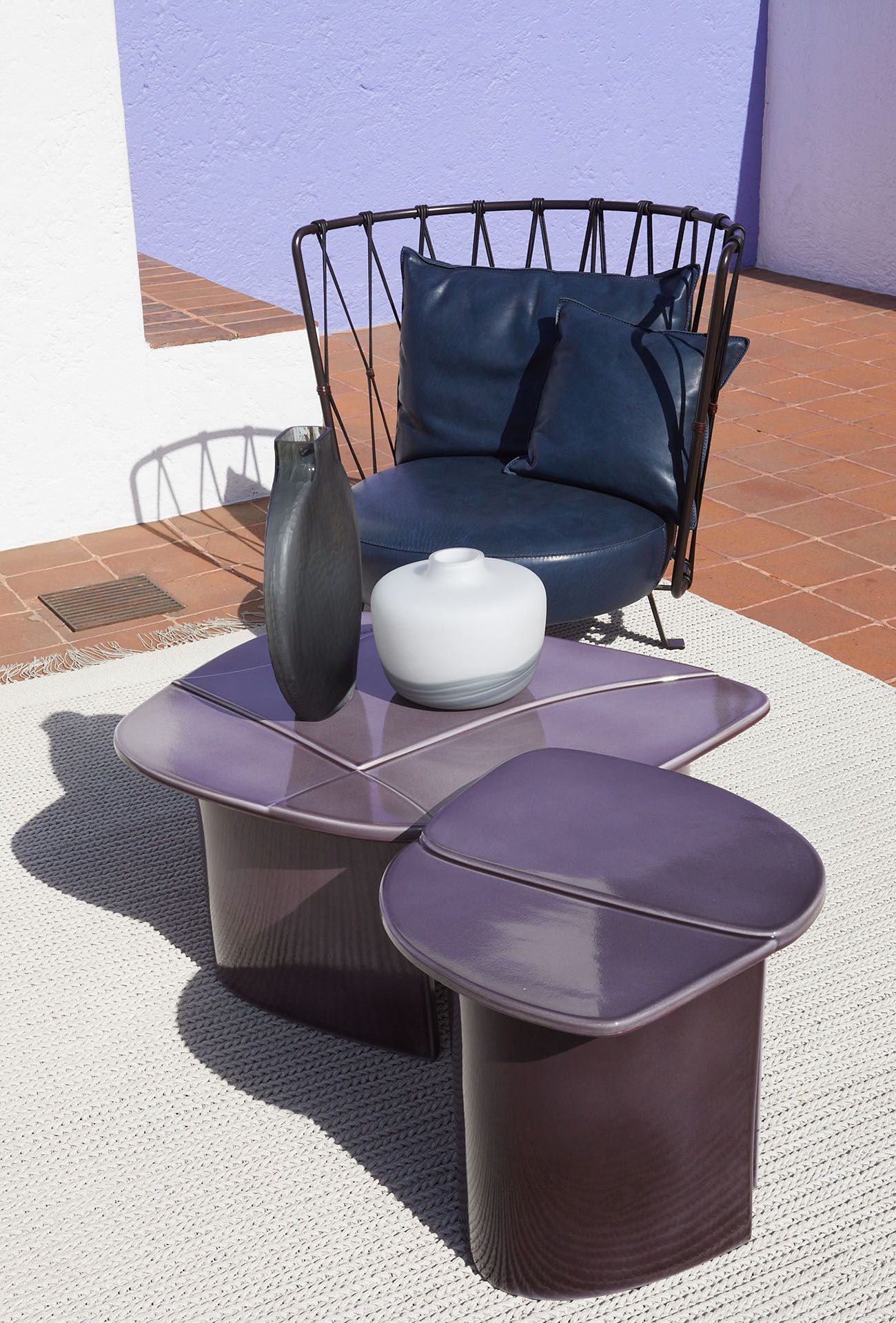 Een stoel en twee tafels staan ​​op een kleed op een terras.
