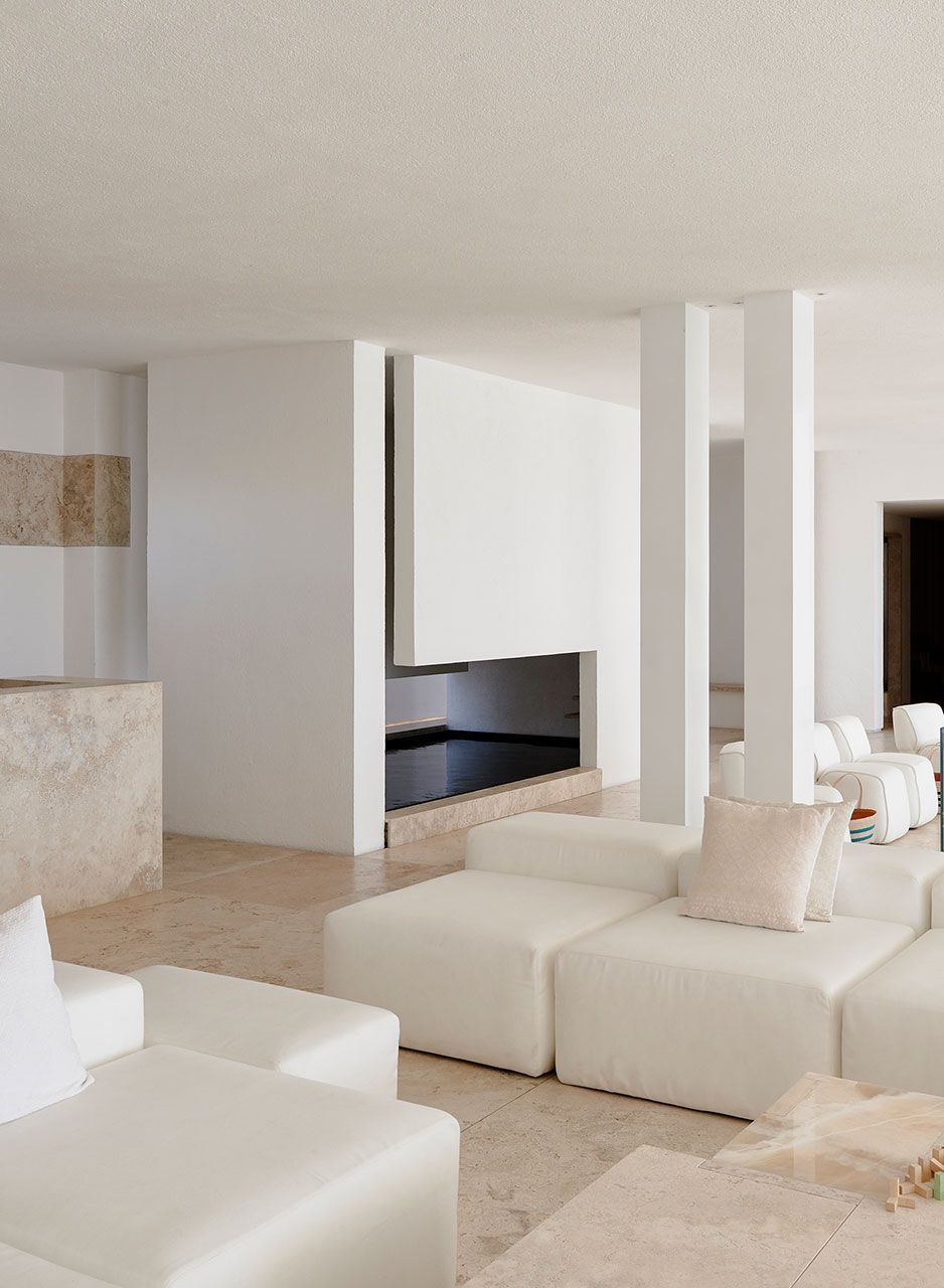 Een woonkamer met witte meubels en een open haard