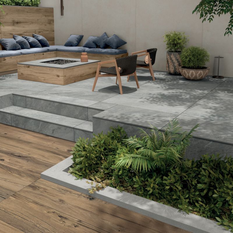 Een terras met een vuurplaats en een houten bank