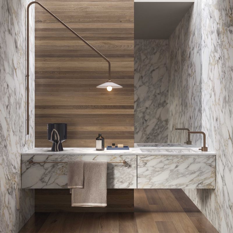 Een badkamer met marmeren aanrechtbladen en een houten muur