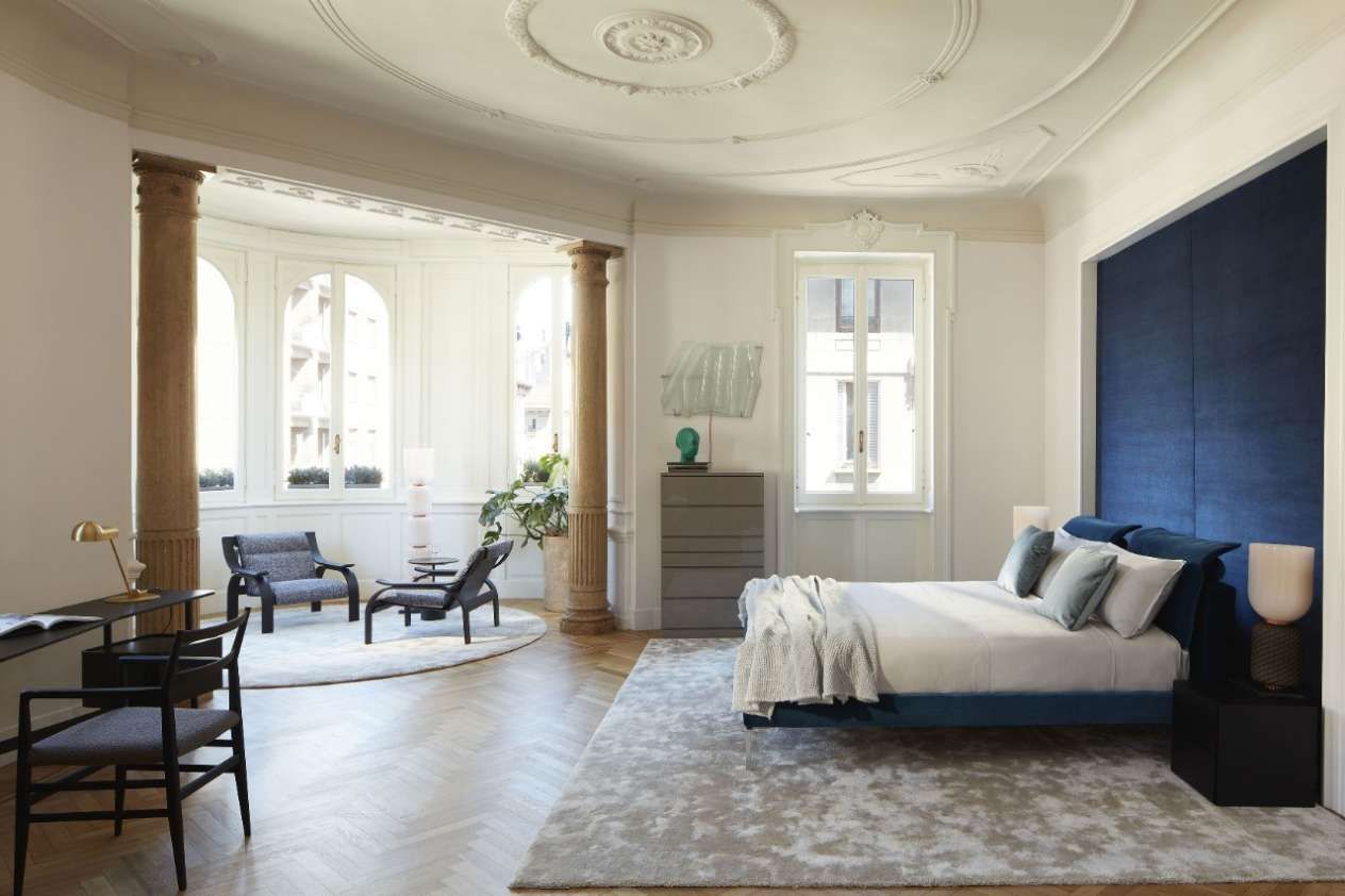 Een slaapkamer met een bed, stoelen en een kleed.