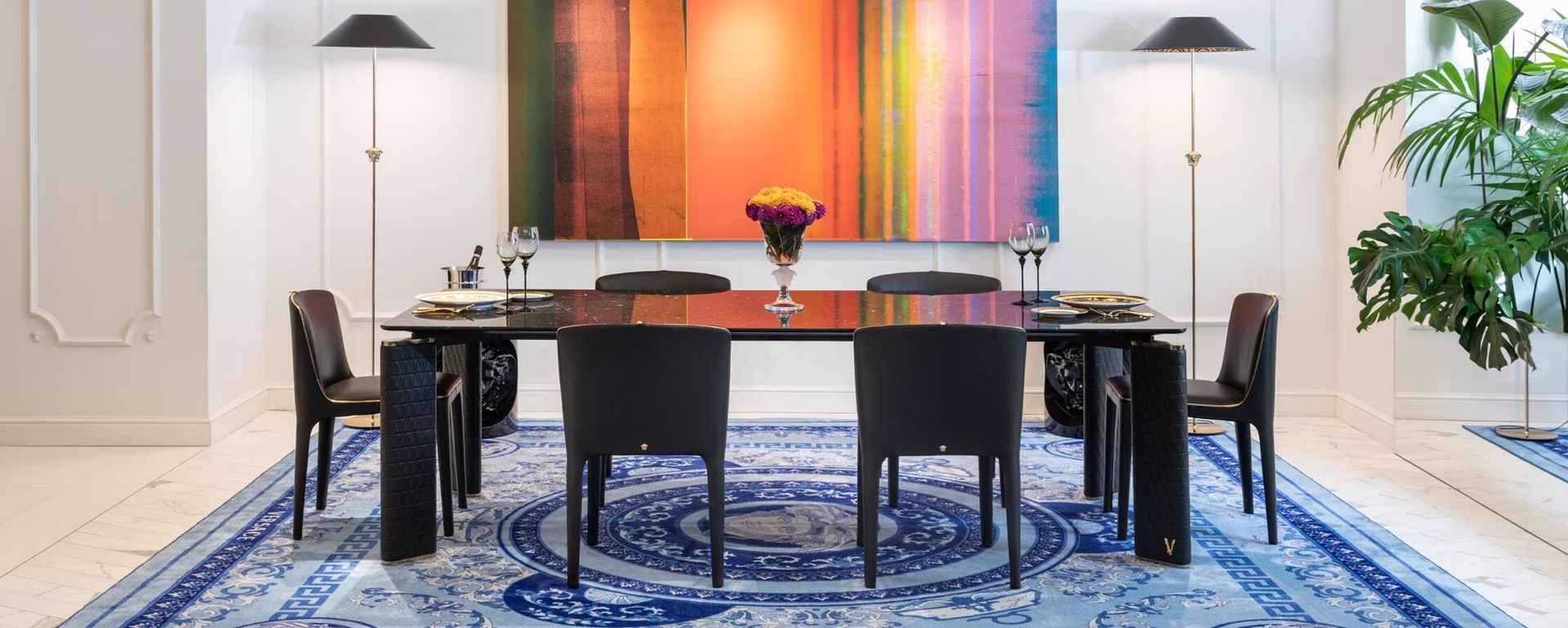 Een eetkamer met een tafel, stoelen en een blauw kleed.
