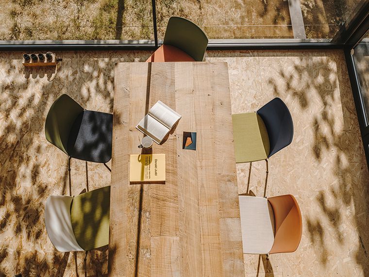 Een houten tafel met vier stoelen en een boek erop.