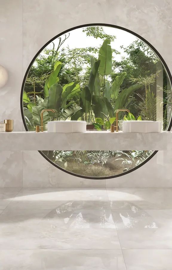 Een badkamer met twee wastafels en een groot rond raam.