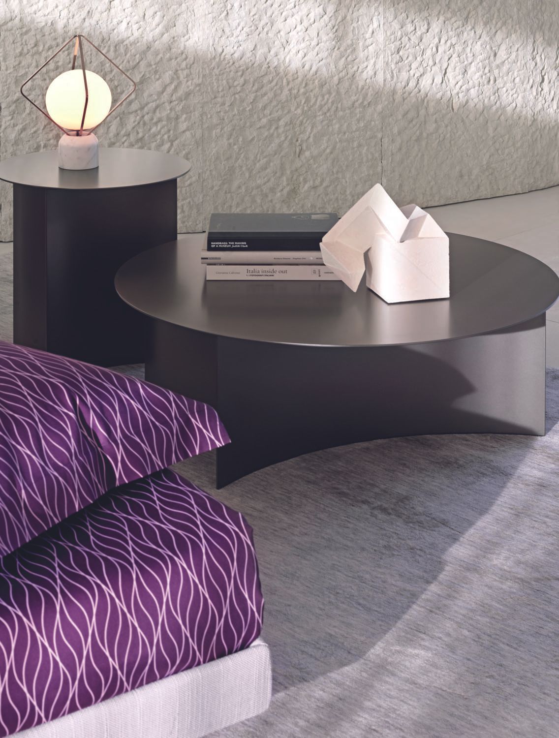 Een slaapkamer met paarse lakens en een ronde salontafel