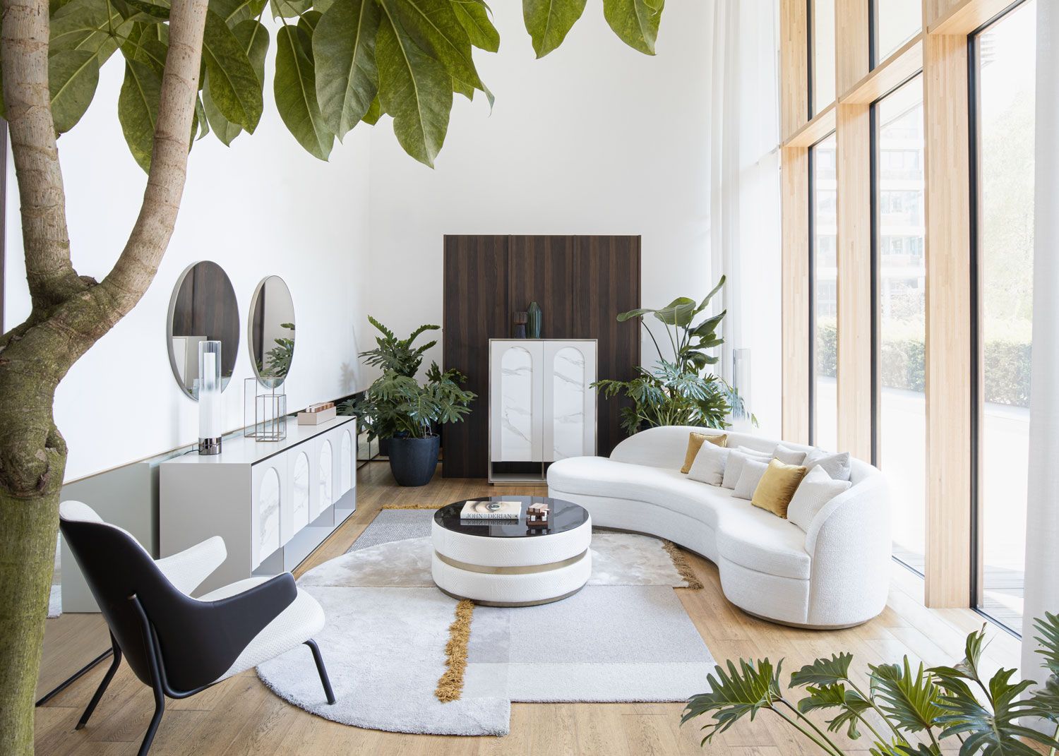 Een woonkamer met een gebogen bank, stoel, salontafel en spiegels.