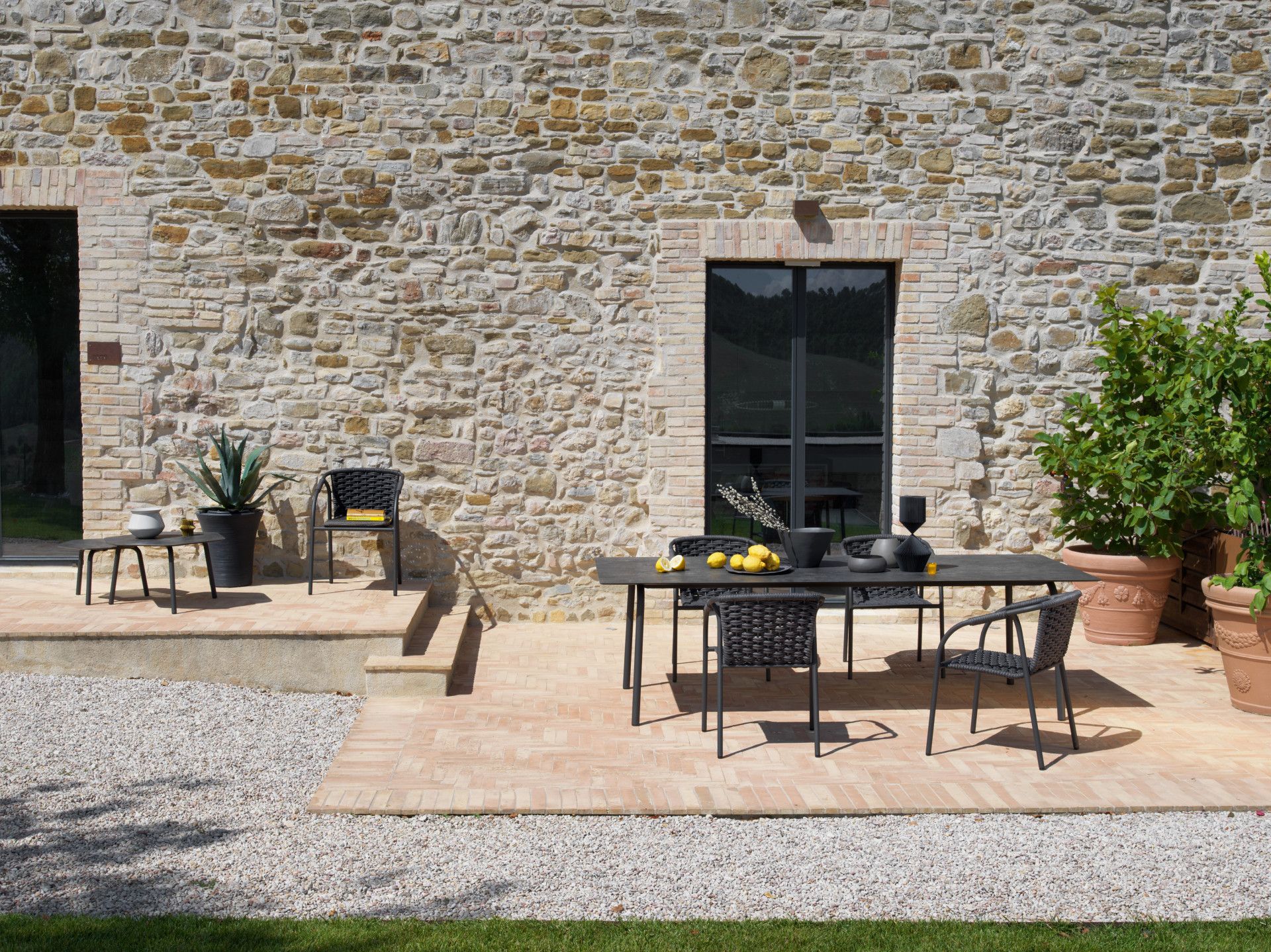 Een terras met een tafel en stoelen voor een stenen gebouw.