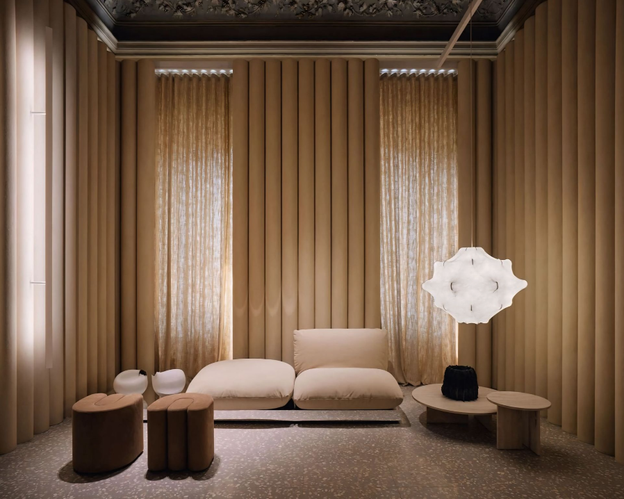Een woonkamer met een bank, poefs, tafels en een lamp.