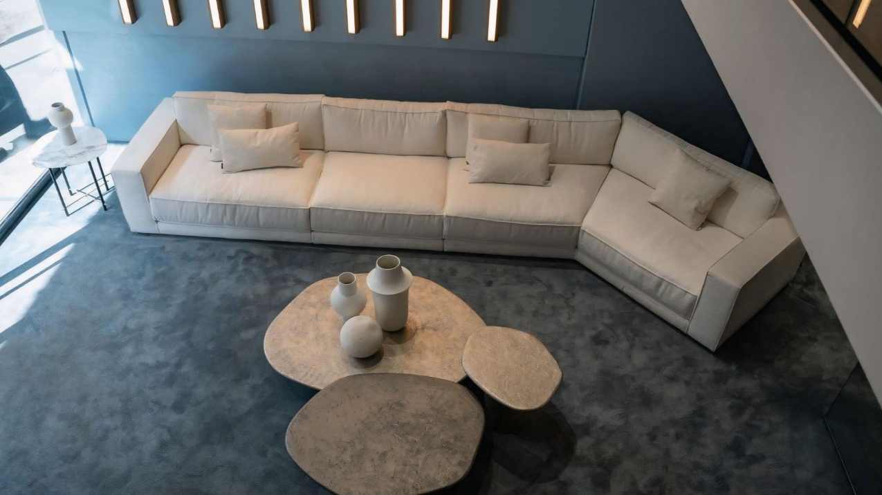 Een woonkamer met een grote witte hoekbank en twee salontafels.