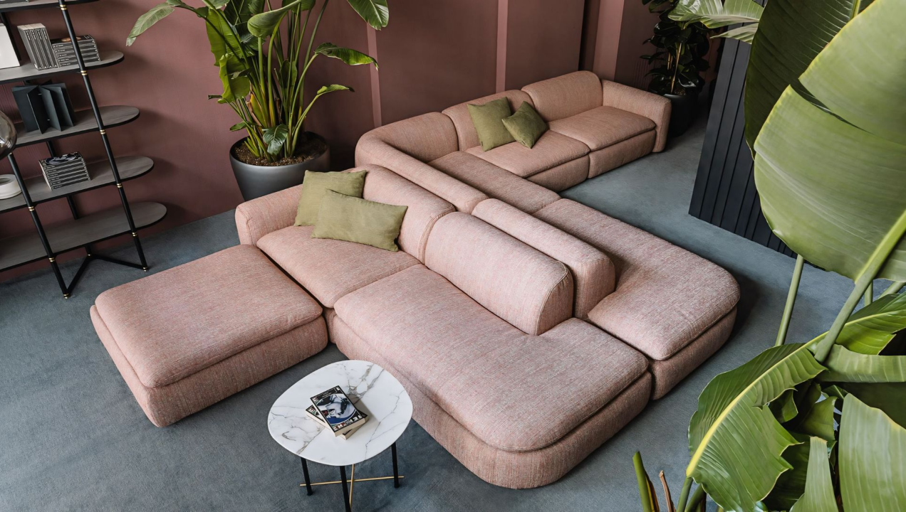 Een woonkamer met een roze bank en een tafel.