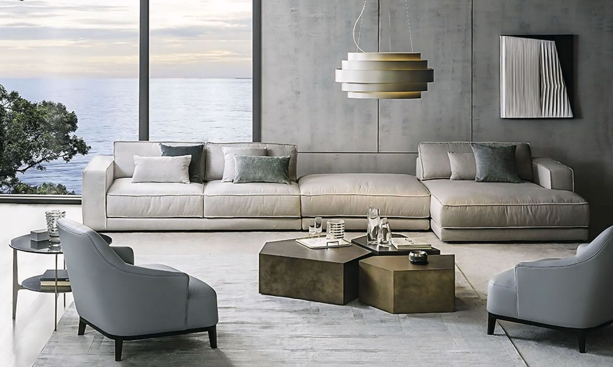 Een woonkamer met een bank, stoelen, tafels en een groot raam met uitzicht op de oceaan.