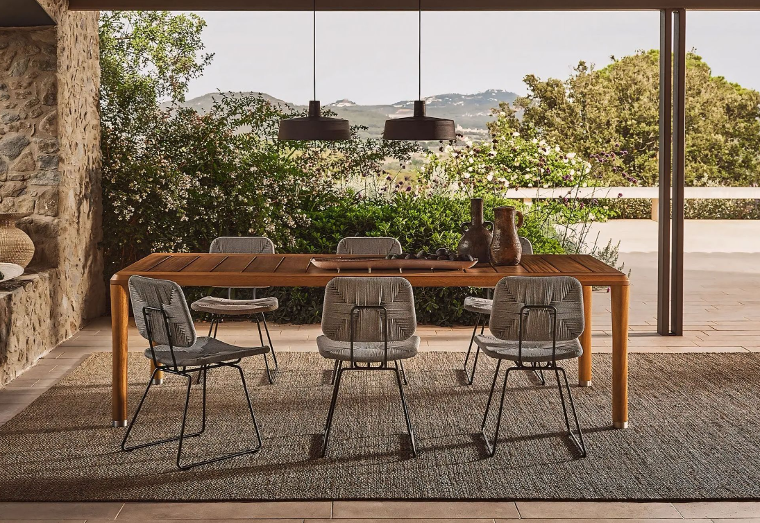 Een eetkamer met een houten tafel, stoelen en een tapijt.