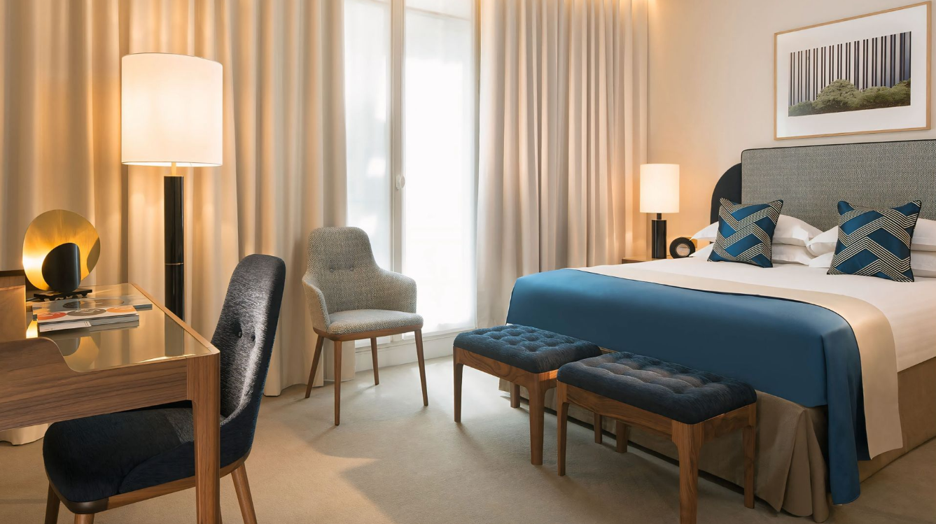 Een hotelkamer met een kingsize bed, bureau, stoelen en een bank.
