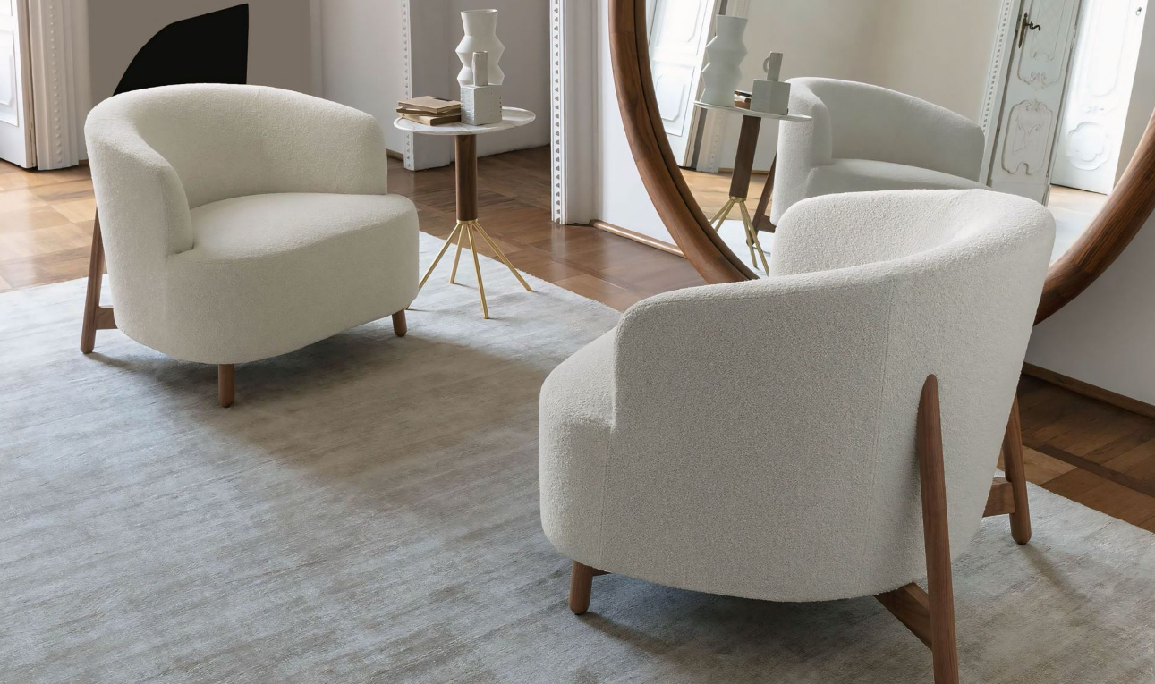 Twee witte stoelen staan ​​in de woonkamer naast een spiegel.