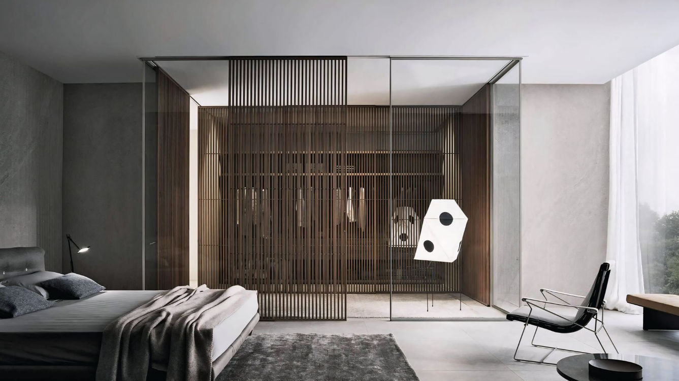 Een slaapkamer met een bed, een stoel en glazen schuifdeuren.
