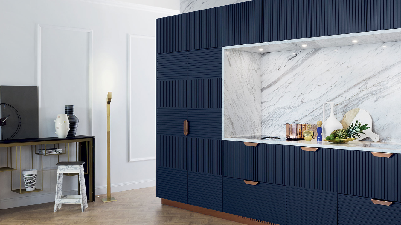 Een keuken met blauwe kasten en een marmeren aanrechtblad.