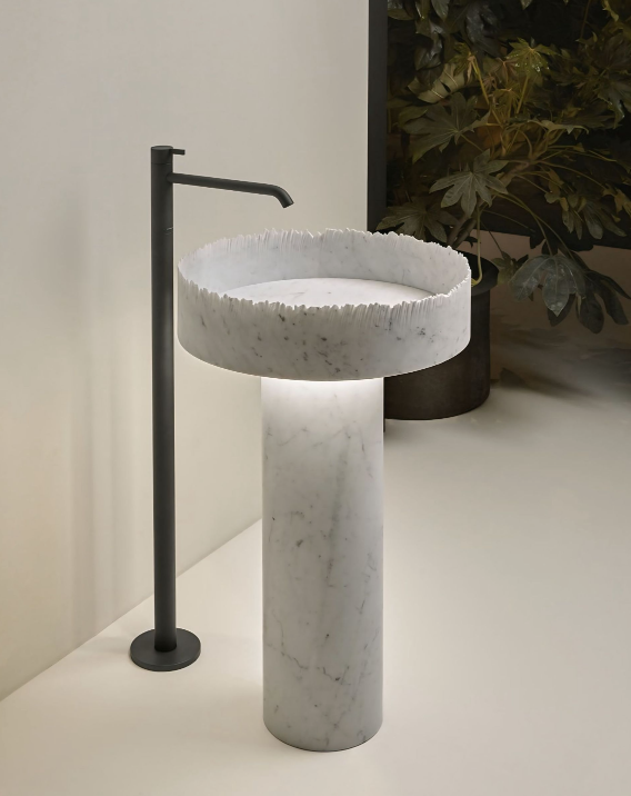 Een witte marmeren wasbak met een zwarte kraan staat op een witte tafel.