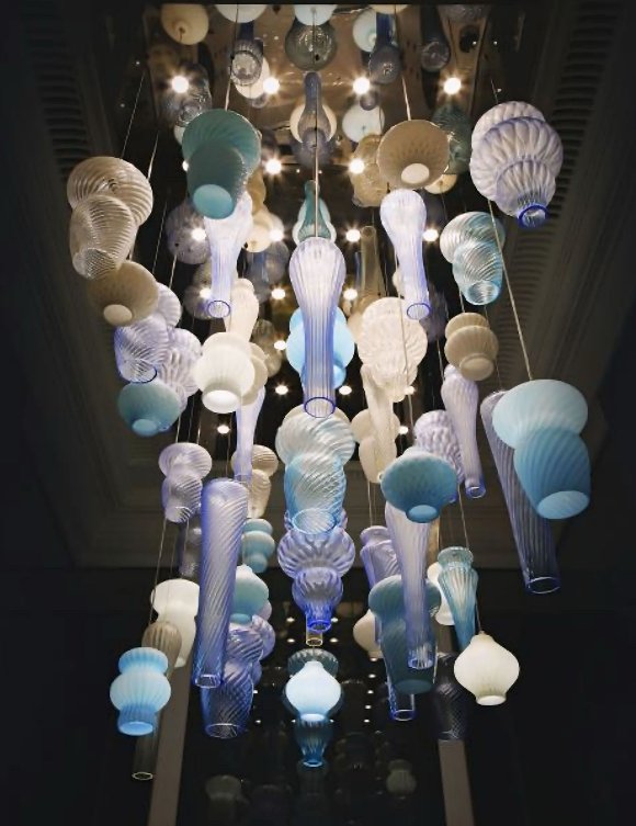 Een kroonluchter met veel verschillende gevormde lampen die aan het plafond hangen