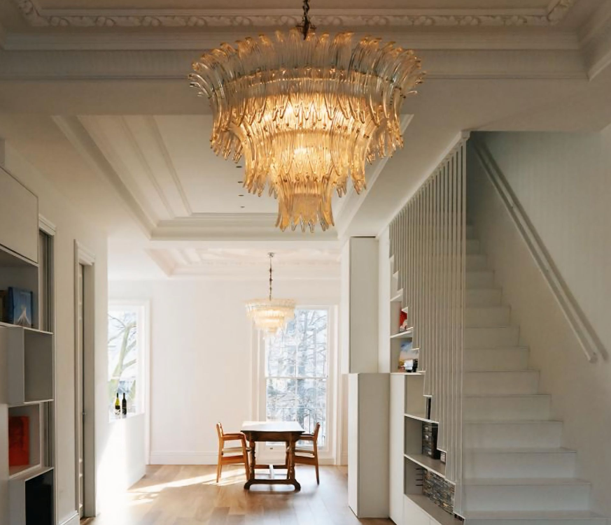 Een eetkamer met een tafel en stoelen en een kroonluchter die aan het plafond hangt