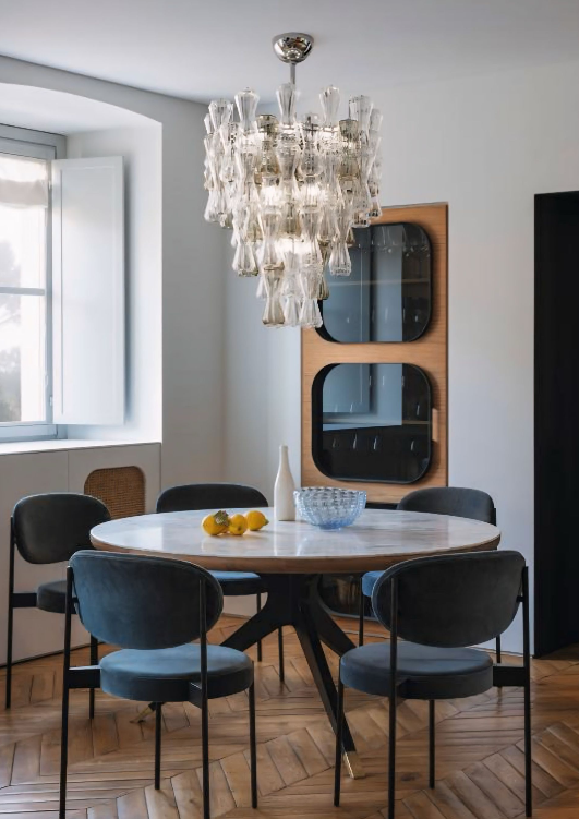 Een eetkamer met een tafel en stoelen en een kroonluchter
