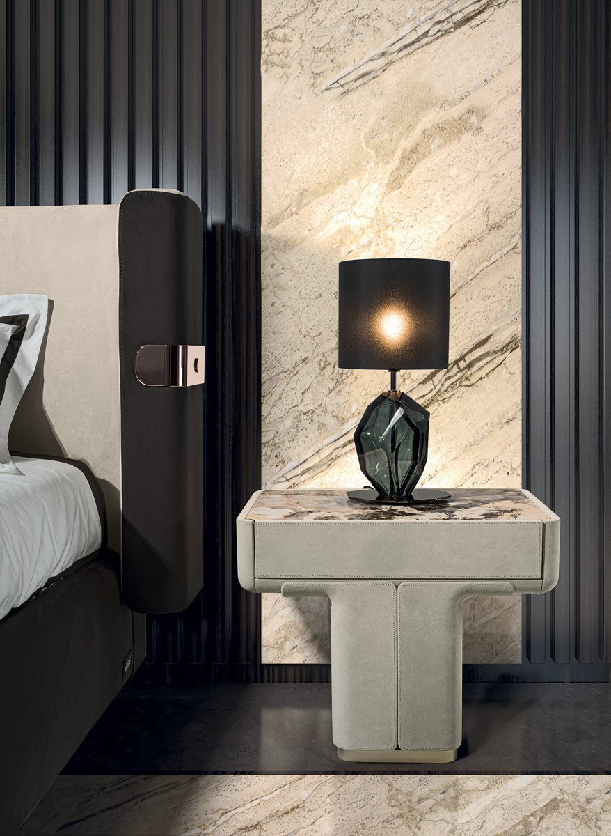Een slaapkamer met een bed en een nachtkastje met een lamp erop.