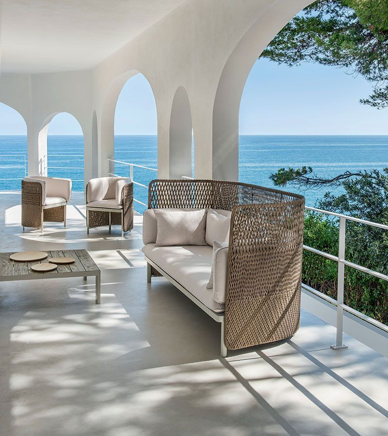Een woonkamer met een bank en stoelen met uitzicht op de oceaan