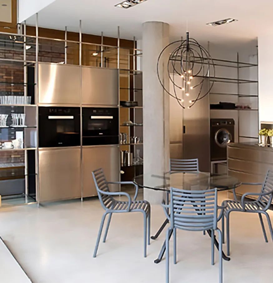 Een keuken met roestvrijstalen apparatuur en een tafel en stoelen