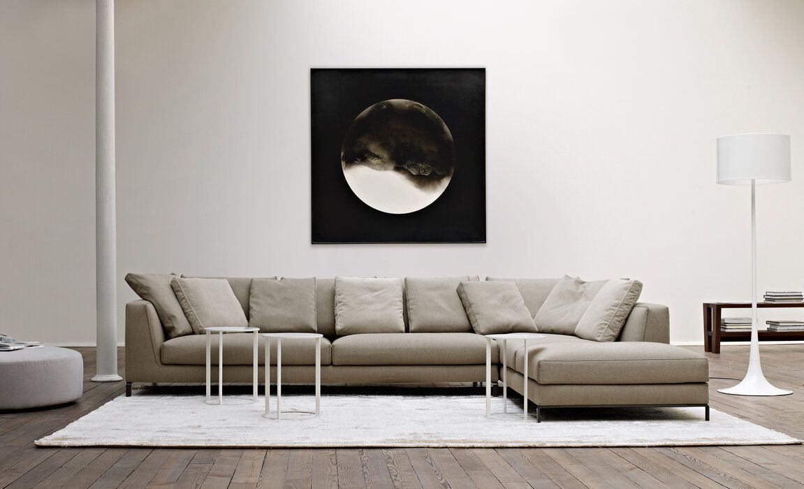 Een woonkamer met een grote hoekbank en een schilderij aan de muur