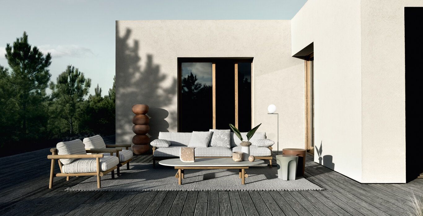 Een terras met een bank, stoelen en een tafel voor een huis.