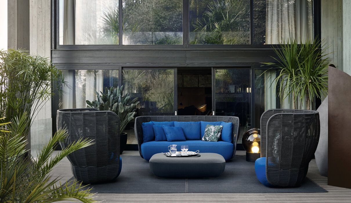 Een terras met een blauwe bank, twee stoelen en een salontafel.